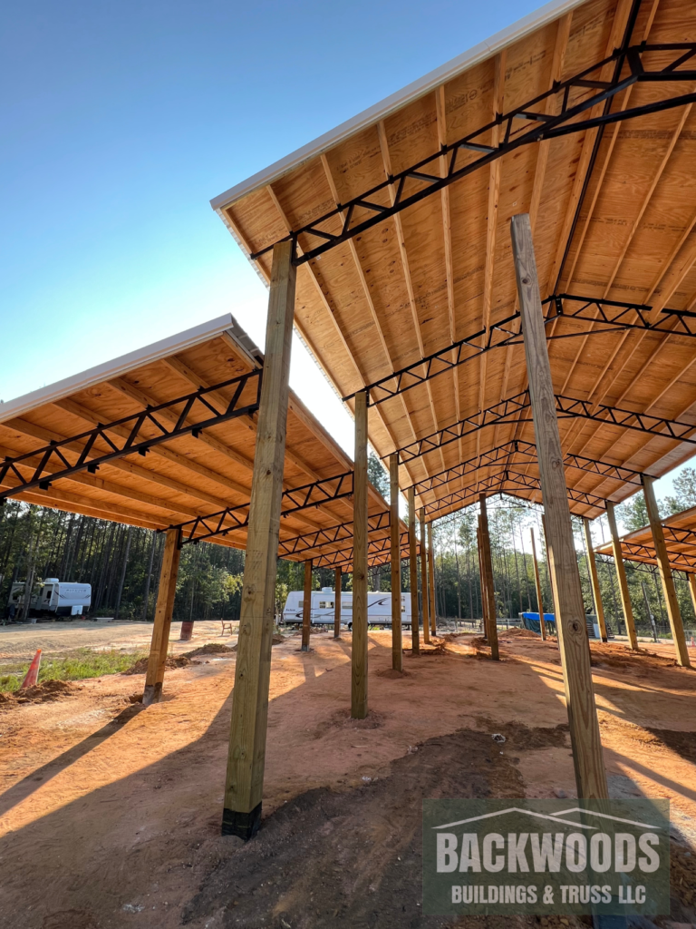 Barndo open pole barn structure with lean-tos and decking on the roof by Backwoods Buildings